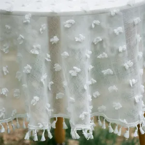 Detailed macro view of white tulle tablecloth with plush tufted flowers and fringe trim