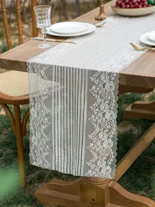 Dettaglio del runner da tavola in pizzo vintage con motivi floreali su tavolo in legno