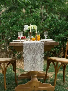 Close-up of white lace table runner with hollow floral embroidery and scalloped edges