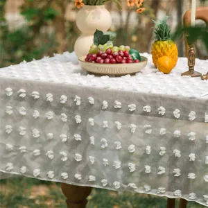 Detail der weißen 3D-Blumenstickerei auf einer beigen rustikalen Netztischdecke für Deko