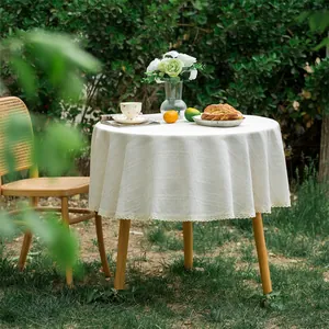 Detailopname van beige rond linnen tafelkleed met kanten randen in een tuinsetting