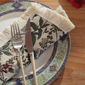 Vintage floral jacquard placemat with cream tassels on wood table with dinnerware