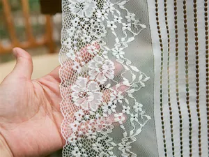 Dettaglio del tessuto in pizzo bianco con delicati ricami floreali trasparenti