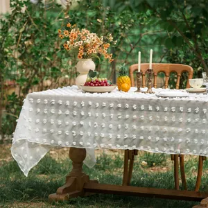 Detail der weißen Netztischdecke mit 3D-Blumenstickerei und strukturierten Pompons