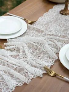 Close-up of white floral lace table runner with scalloped edges on a wooden dining table