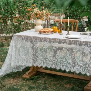 Detailed view of white floral lace tablecloth with elegant scalloped edges on outdoor table