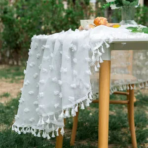 Detail of white Swiss dot tablecloth featuring delicate fringe tassels for weddings