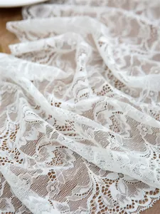 Close-up of white floral lace fabric with intricate hollow patterns on a wooden surface