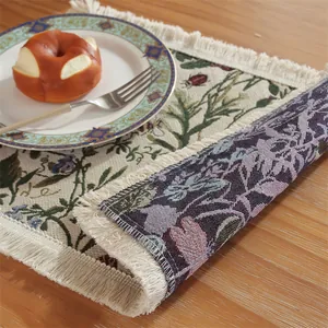 Vintage jacquard placemat with floral beetle pattern and white tassels on a wooden table