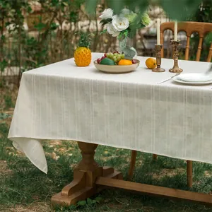 Detailopname van het beige linnen tafelkleed met streeptextuur op een tuintafel