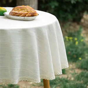 Detail van beige rond tafelkleed met kanten rand en geweven gestreepte textuur