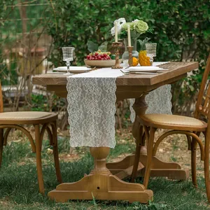 Elegant white lace floral table runner on a wooden table in an outdoor garden setting
