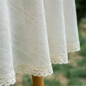 Detail van beige tafelkleed met fijn kant en een getextureerde linnen weving