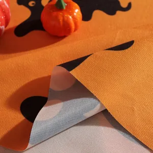 Close-up of orange Halloween tablecloth fabric texture with black pumpkin print