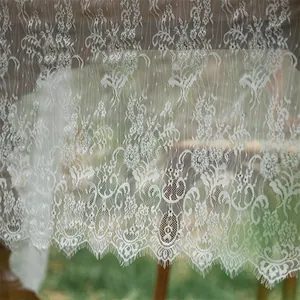 Detailed macro view of white lace tablecloth with floral embroidery and eyelash edges