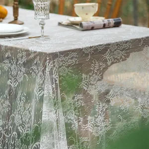 Detailed close-up of intricate white lace floral patterns on a vintage French tablecloth