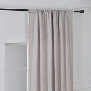 Detail der grauen Jacquard-Gardine mit Rautenstruktur und beigen Fransenquasten