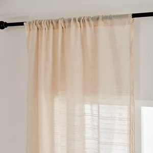 Détail d'un rideau en lin beige semi-transparent avec bordure en dentelle et passe-tringle