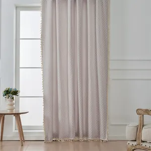 Detail eines hellgrauen Jacquard-Vorhangs mit eleganten cremefarbenen Quastenfransen