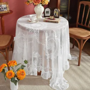 Close-up of white French lace tablecloth with floral patterns and ruffled edges