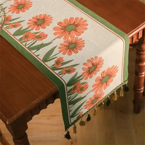 Dettaglio di runner da tavola jacquard retrò con motivi a margherita e nappine bicolore