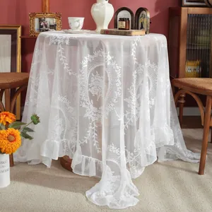 Detailed macro view of white lace tablecloth with vintage rose patterns and ruffled edges