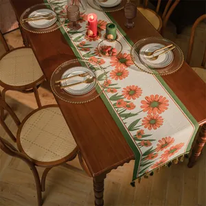 Dettaglio di runner da tavola vintage con jacquard floreale arancione e nappe verdi