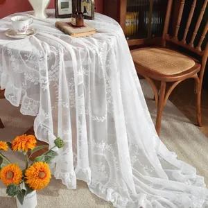 Detailed view of white vintage lace tablecloth with rose floral patterns and ruffled edges