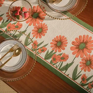 Dettaglio del runner da tavola jacquard con motivo floreale arancione e foglie verdi