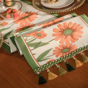 Dettaglio del runner da tavolo jacquard con motivo floreale arancione e nappe decorative