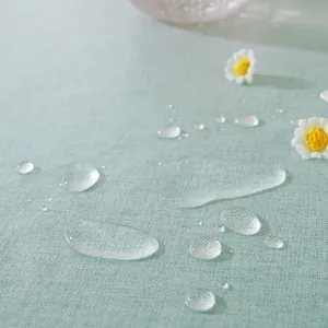 Nahaufnahme der minzgrünen wasserdichten Tischdecke mit Wassertropfen auf Leinenstruktur