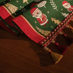 Dettaglio macro del runner natalizio con motivi a maglia di Babbo Natale e nappe bicolore
