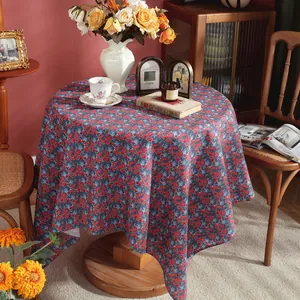 Detail view of cotton linen tablecloth with red and blue floral print on round table