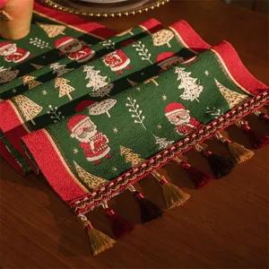 Dettaglio macro del runner da tavola natalizio con ricami jacquard e nappe festive