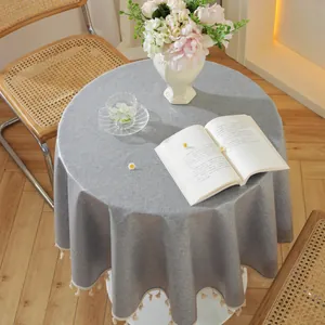 Detail der grauen runden Tischdecke mit Baumwoll-Leinen-Struktur und eleganten Fransen