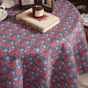 Detail of round cotton linen tablecloth with vintage red floral print on blue background