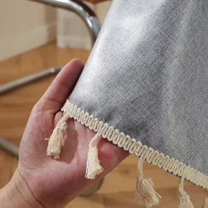 Detailaufnahme der grauen Polyester-Tischdecke mit feiner Webstruktur und cremefarbenen Quasten