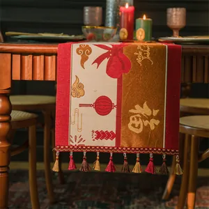 Dettaglio di runner da tavola jacquard rosso e oro con segno Fu e bordo con nappe