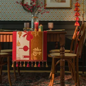 Dettaglio del runner da tavola rosso festivo con ricamo jacquard dorato e nappe intrecciate