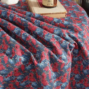 Detail of vintage blue linen tablecloth with dense red floral prints and drape