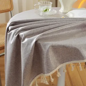 Detailaufnahme der runden Tischdecke mit Leinentextur und weißen Quasten am Rand