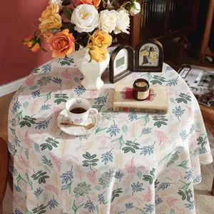 Detailed top view of a cream round linen tablecloth with colorful floral leaf patterns