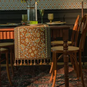 Dettaglio macro del runner da tavolo jacquard vintage con motivi floreali e nappe