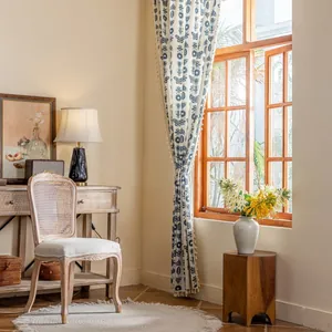 Close-up of cream curtain featuring blue floral prints and delicate decorative tassels