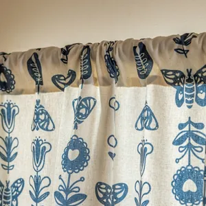 Close-up of beige linen curtain with blue folk art butterfly patterns and rod pocket style