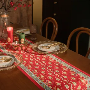 Dettaglio del runner da tavola rosso con motivi jacquard e posate d'oro su legno