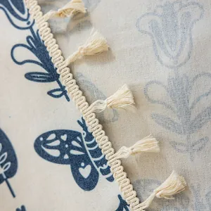 Detail of printed cotton linen fabric with blue butterfly pattern and beige tassel fringe