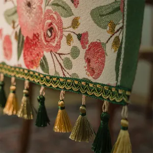 Dettaglio del runner da tavola vintage con motivi a rose rosse e nappe dorate