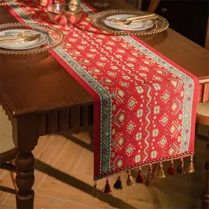 Runner da tavola etnico con motivo jacquard rosso e nappe su un tavolo in legno scuro