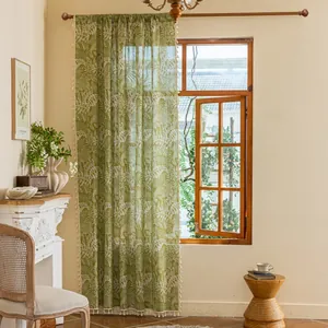 Close-up of light green semi-sheer curtain with leaf patterns and small pom-pom tassels